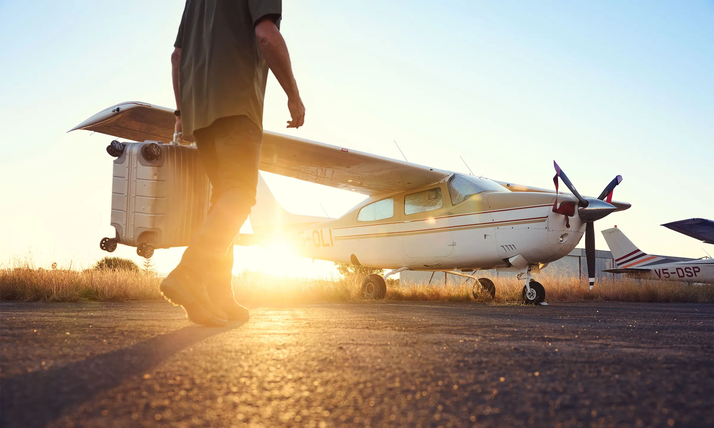 Man carrying trolley in front of Cessna at sunset